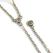 A close up detail of the round brilliant bezel-set lariat necklace.