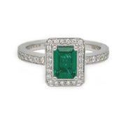 Emerald center stone surrounded by a halo of round diamonds, set in a white gold band.