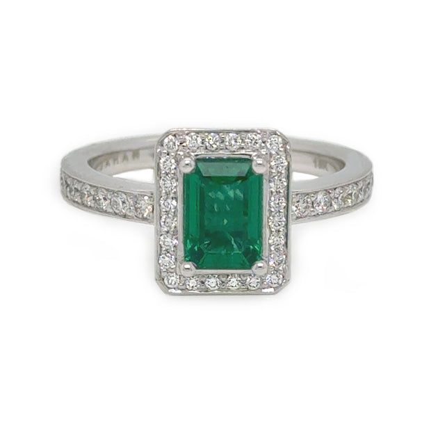Emerald center stone surrounded by a halo of round diamonds, set in a white gold band.
