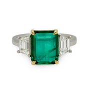 Ring with a green emerald gemstone and diamonds on a white background