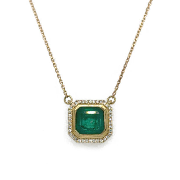 Close-up of the Asscher Cut Green Emerald Necklace, highlighting the vibrant 1.80 ct emerald surrounded by radiant diamonds in a refined 18K yellow gold setting.