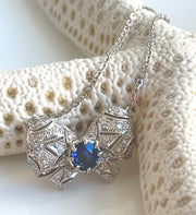 Blue sapphire and diamond bow motif necklace.