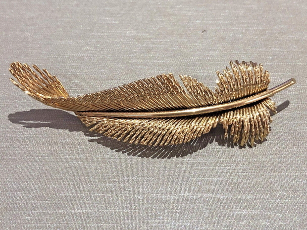 A luxurious, solid gold brooch with exquisite detail and graceful form.
