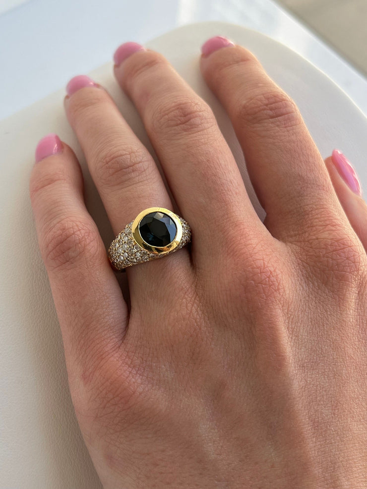 he ring shown worn on a hand to demonstrate its scale and fit (size 6.5). The sapphire’s bold presence is balanced by the subtle shimmer of diamonds, creating a sophisticated yet eye-catching statement.