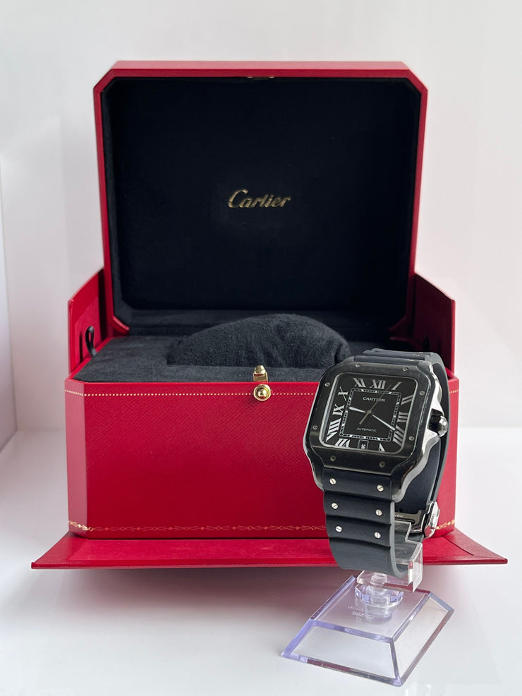 Black Cartier watch on a stand with a red Cartier box in the background.