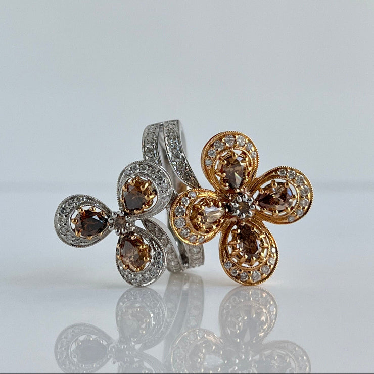 Close-up of pear-shaped chocolate diamonds set in rose gold floral design ring with round white diamond accents.