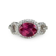 Vibrant oval pink tourmaline gemstone ring in an east west setting accented by diamonds.