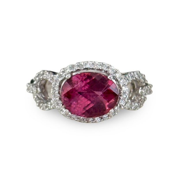 Vibrant oval pink tourmaline gemstone ring in an east west setting accented by diamonds.