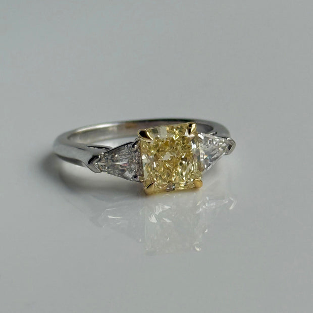 Elegant platinum and yellow gold diamond ring with Fancy Yellow radiant-cut center and kite-shaped side stones