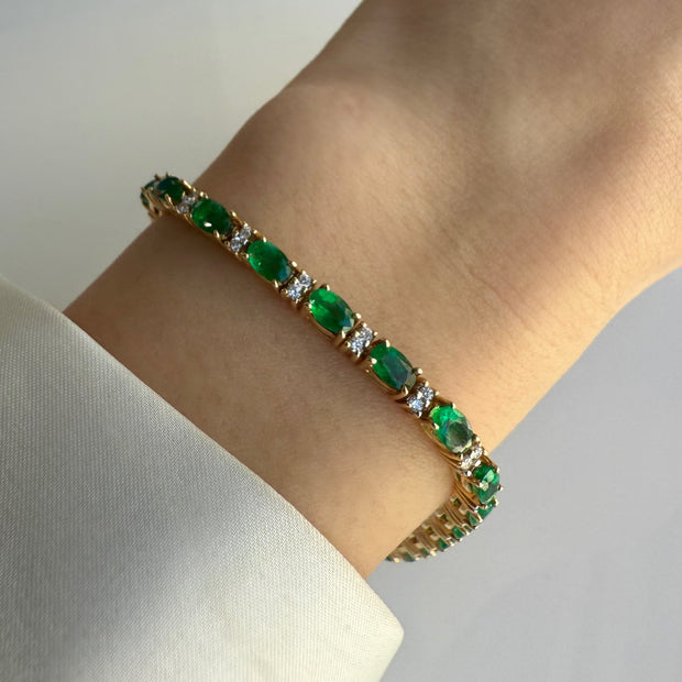 A model wearing the oval emerald and diamond bracelet, showcasing how it adds a touch of elegance to an outfit.