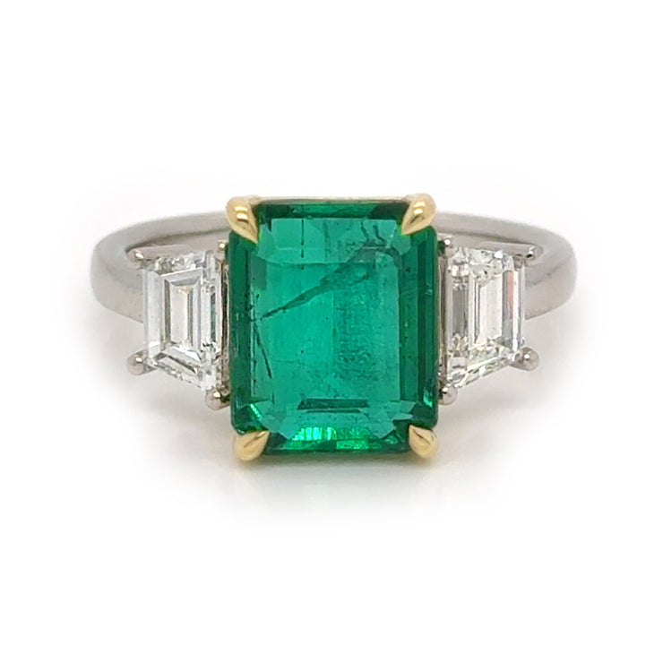 A dazzling emerald ring with two trapizoid diamond accents.