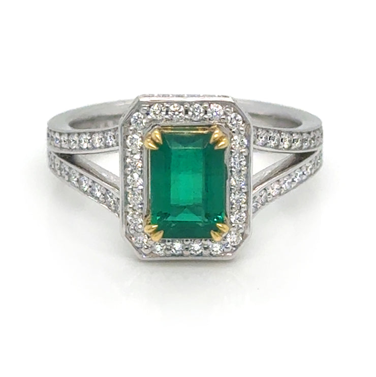 An elegant ring featuring a 1.01-carat emerald at the center, surrounded by 0.50 carats total weight of round diamonds. The stones are set in an 18k two-tone gold band, showcasing a sophisticated contrast between white and yellow gold.