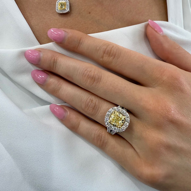 Model wearing a halo ring featuring a 3.01 CT fancy yellow diamond with round brilliant accents in two-tone 18K gold.