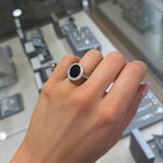 Oval sapphire bezel-set diamond ring in platinum with yellow gold detailing shown on hand