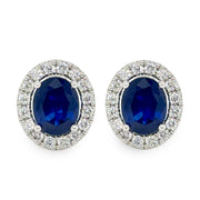Pair of earrings with blue sapphire gemstones and silver surrounds on a white background