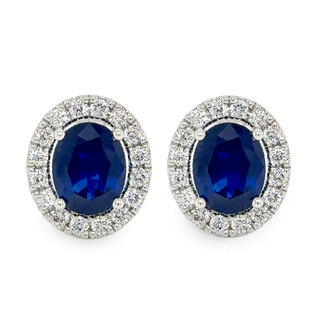 Pair of earrings with blue sapphire gemstones and silver surrounds on a white background