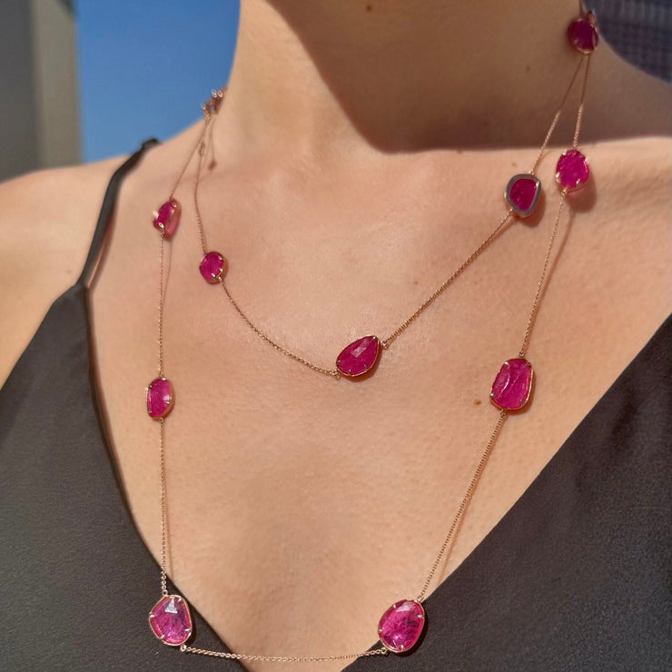 Necklace with red ruby slice gemstones worn by a model against a blue sky.