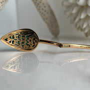 Detailed engraving on the interior of yellow gold bangle with turquoise showing clasp