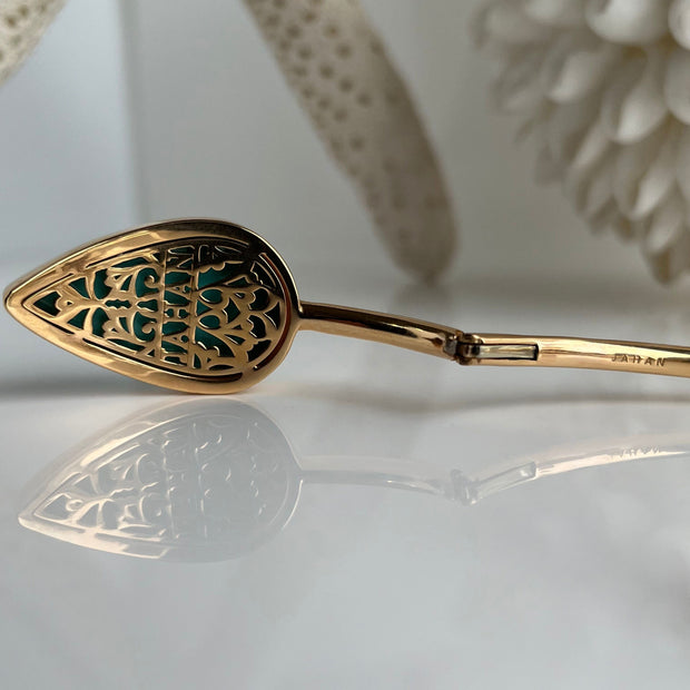 Detailed engraving on the interior of yellow gold bangle with turquoise showing clasp