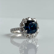 Side view of blue sapphire halo ring with round brilliant diamonds in white gold setting