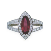 Ring with a marquise-shaped pink tourmaline gemstone and diamond-studded band on a white background