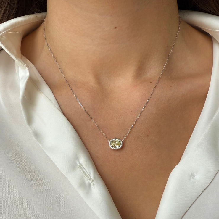 Necklace with a yellow diamond pendant worn by a person in a white silk shirt