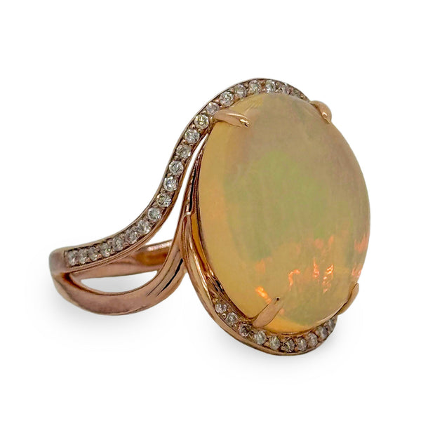 A 6.30 ct opal shimmering with shifting hues, surrounded by delicate diamonds in 14K rose gold.