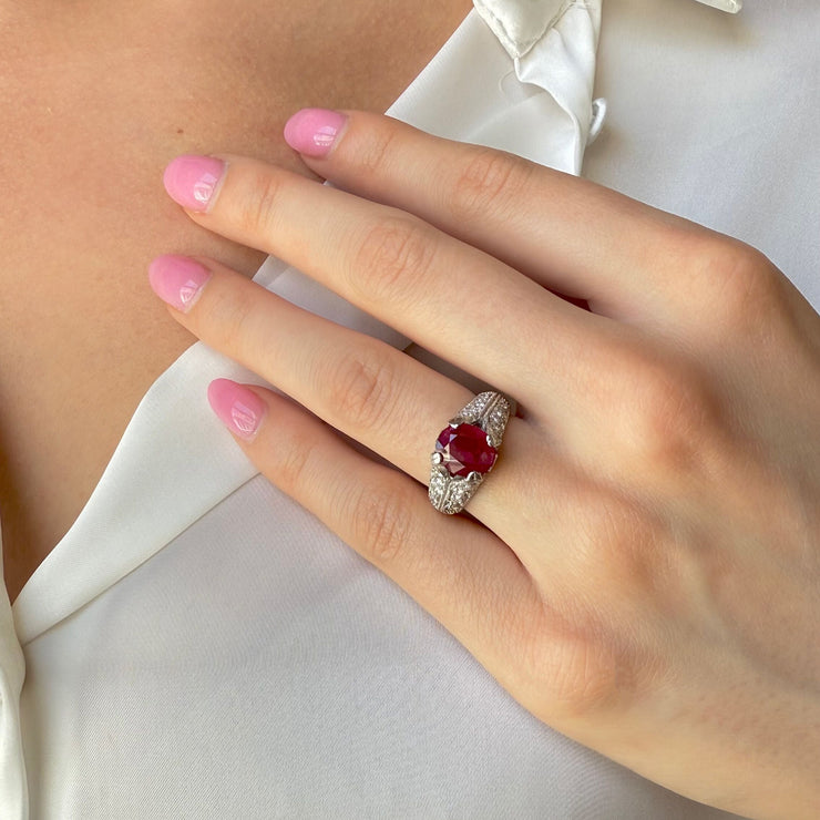 Ruby and diamond ring on model’s hand, featuring 1.96 ct oval ruby in 14k white gold with engraved milgrain band.