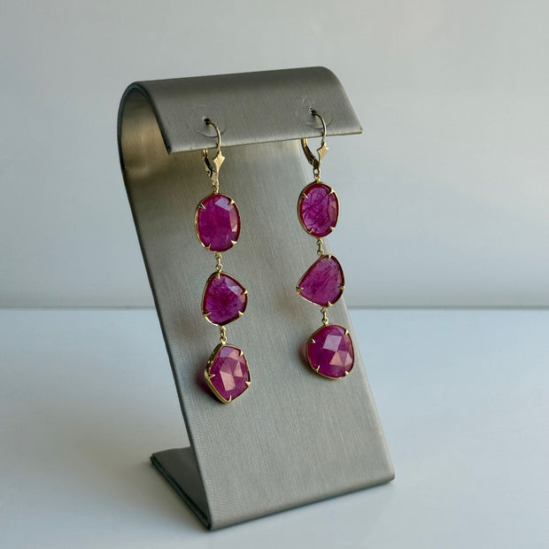 Elegant ruby drop earrings displayed on a luxury gray display stand