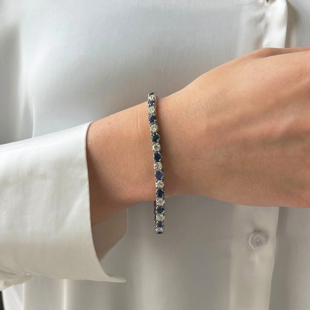 Model wearing a deep blue sapphire and diamond tennis bracelet on their wrist