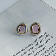 Pair of diamond earrings with pink sapphire gemstones on a book page