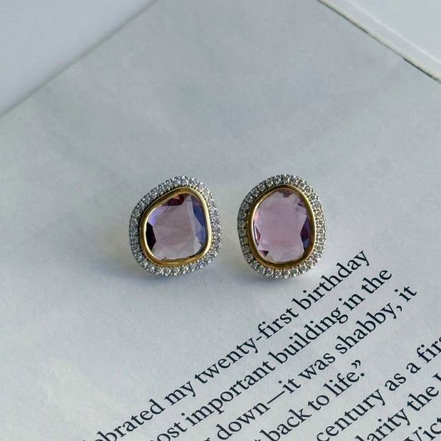 Pair of diamond earrings with pink sapphire gemstones on a book page