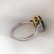 Side view of Emerald two-tone ring with diamond accents on silk