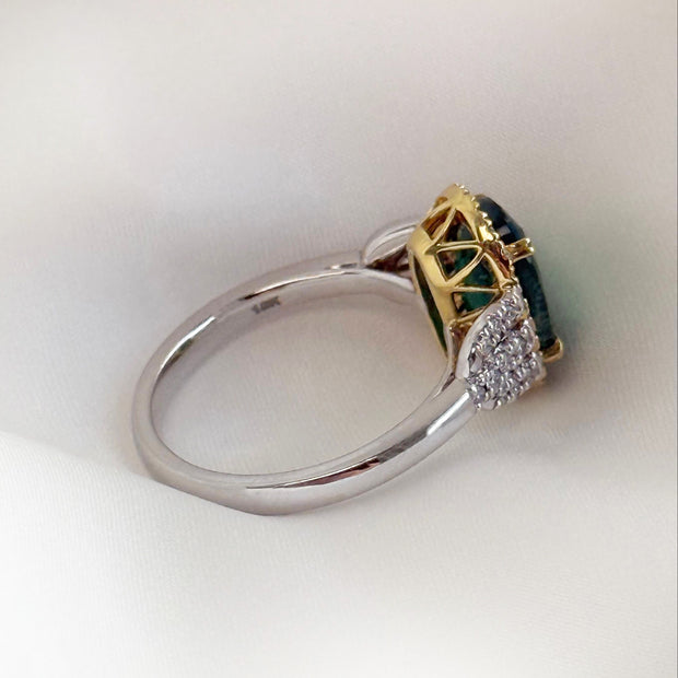 Side view of Emerald two-tone ring with diamond accents on silk