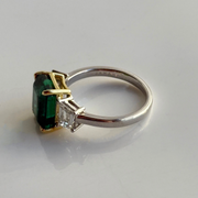 White gold and ring with green emerald gemstone in a yellow gold setting