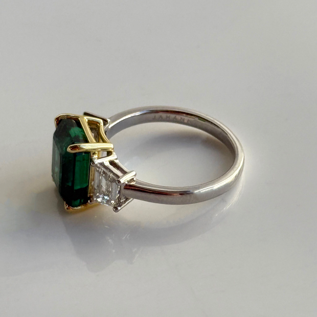 White gold and ring with green emerald gemstone in a yellow gold setting