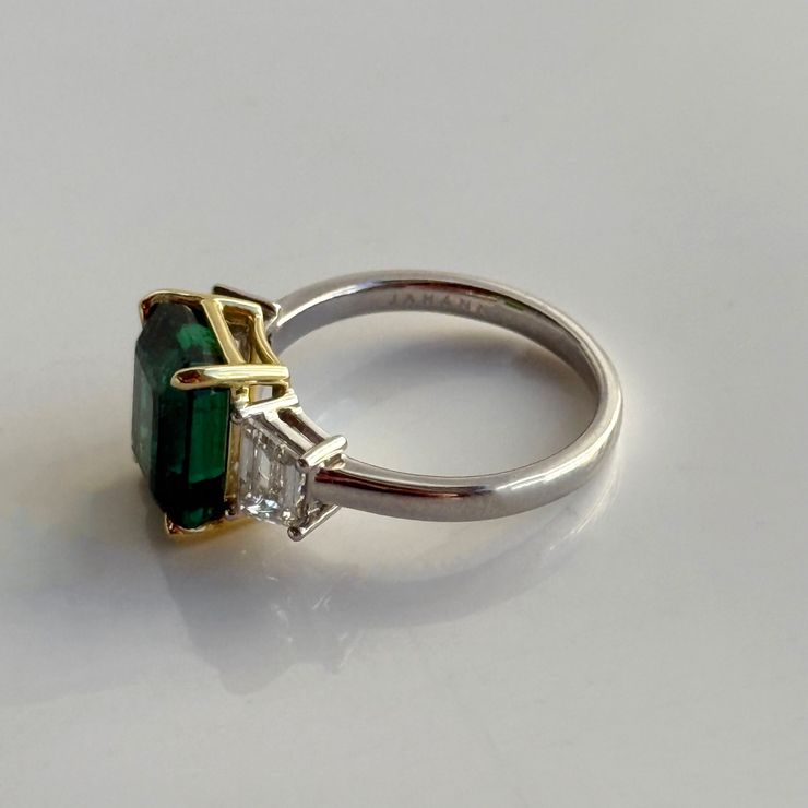 White gold and ring with green emerald gemstone in a yellow gold setting