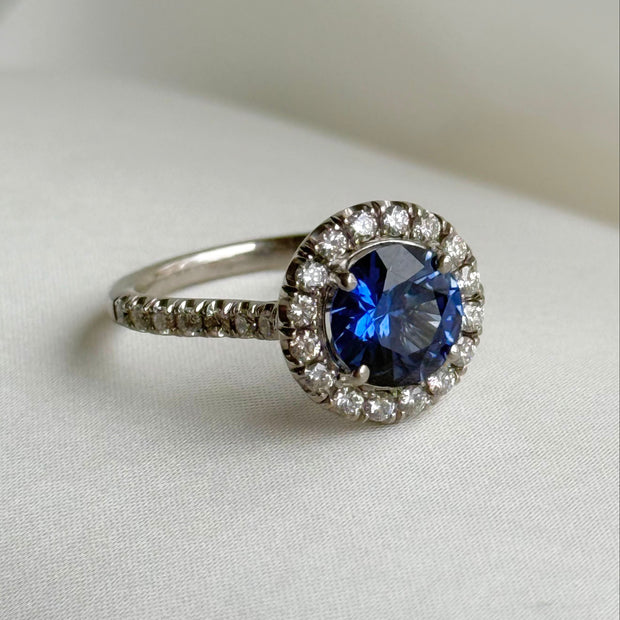 Side view of blue sapphire halo ring showing diamond-studded band detail