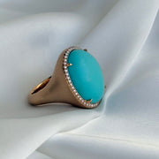 Side view of 18k rose gold ring with matte finish and halo-set turquoise gemstone