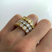 Stacked gold rings with diamonds on a finger against a white background