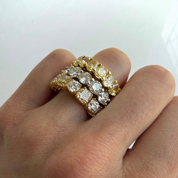Stacked gold rings with diamonds on a finger against a white background