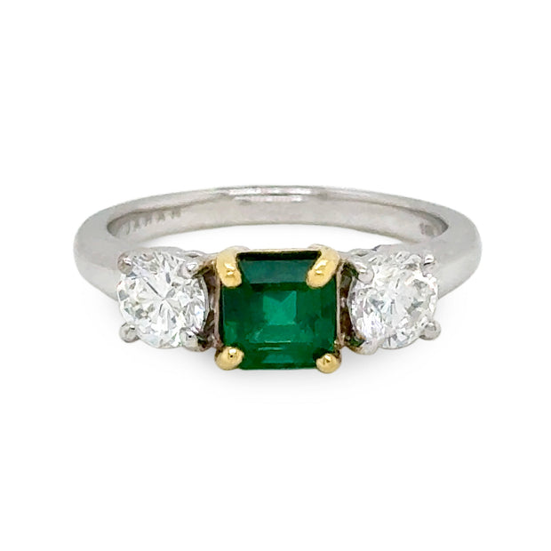 Ring with a green emerald gemstone and two diamonds on a white gold band