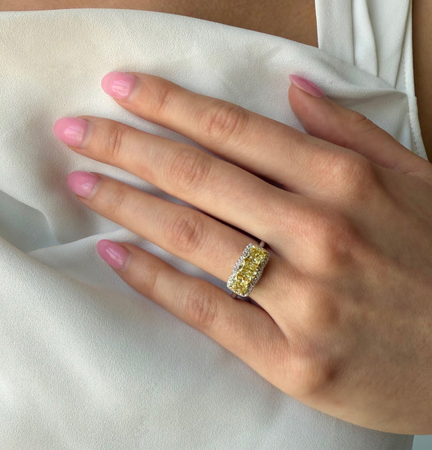 Model wearing three-stone Fancy Yellow diamond ring with round diamond accents, set in 18K two-tone gold.