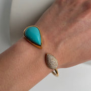 Turquoise and diamond bracelet in yellow gold featuring bezel-set pear turquoise center on model