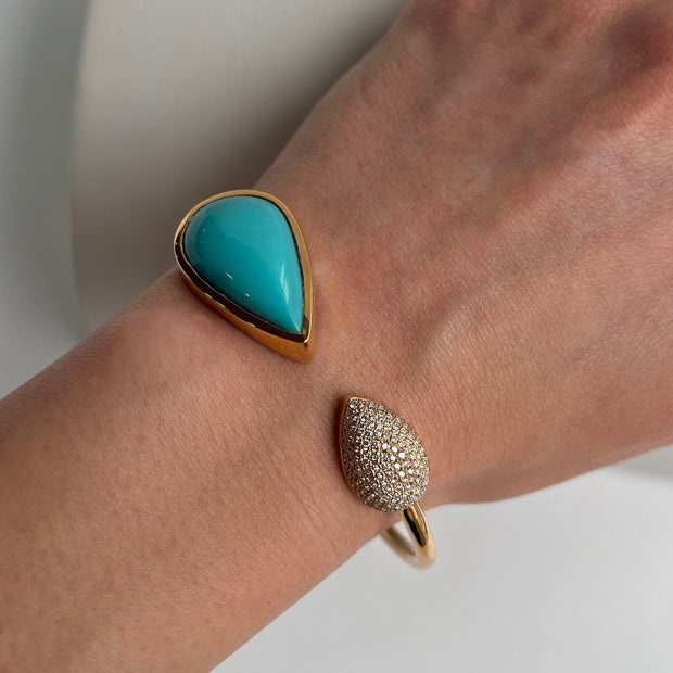 Turquoise and diamond bracelet in yellow gold featuring bezel-set pear turquoise center on model