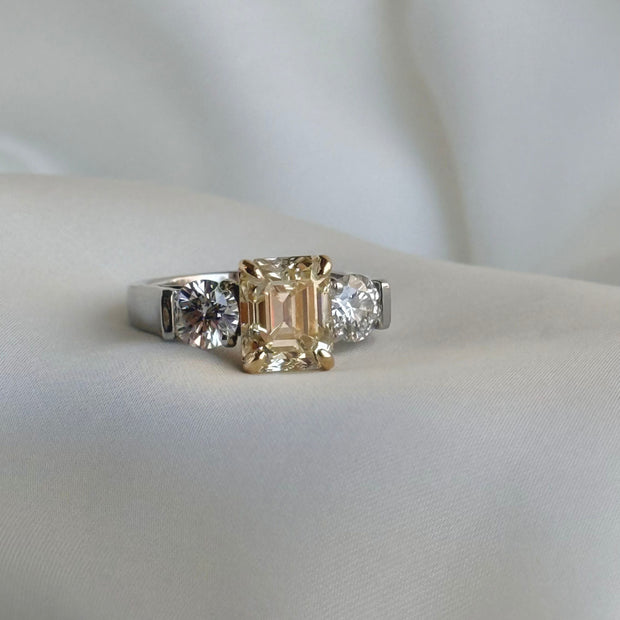 Two-tone platinum and yellow gold ring with emerald-cut Fancy Yellow diamond and round side stones