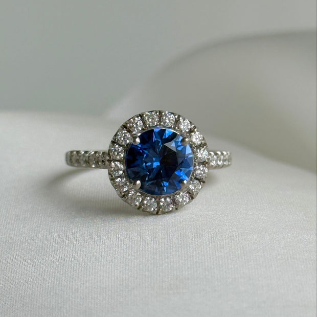 Close-up of 2.01 carat oval blue sapphire ring with diamond halo and pavé diamond band