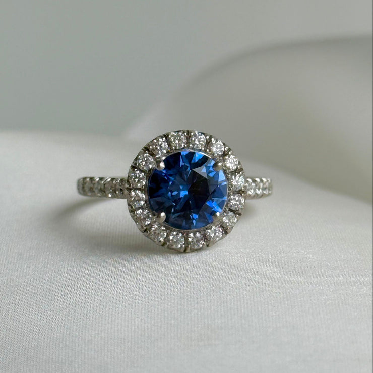Close-up of 2.01 carat oval blue sapphire ring with diamond halo and pavé diamond band