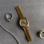 Display showing the petal and diamond setting on a ruby ring along with a rolex watch and diamond bracelet