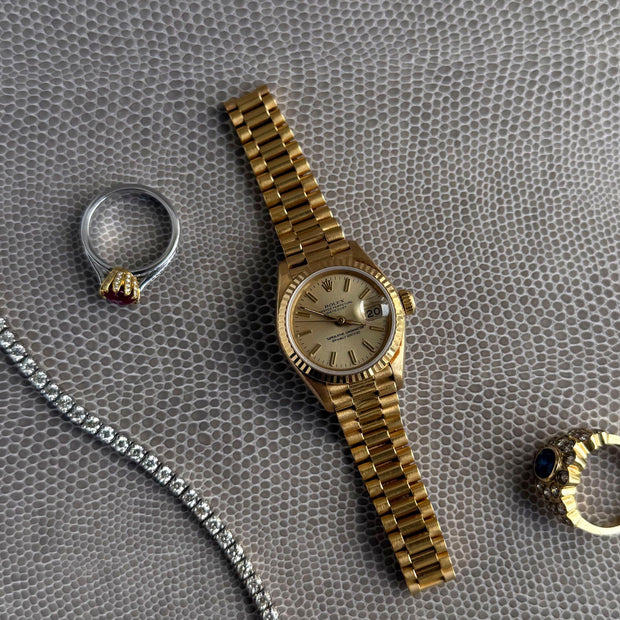 Display showing the petal and diamond setting on a ruby ring along with a rolex watch and diamond bracelet